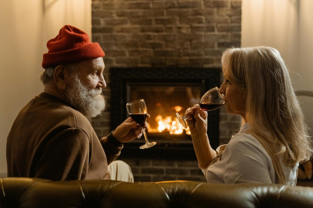 Ein Mann und eine Frau trinken zusammen Wein vor dem Kamin