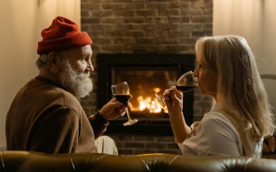 Ein Mann und eine Frau trinken zusammen Wein vor dem Kamin