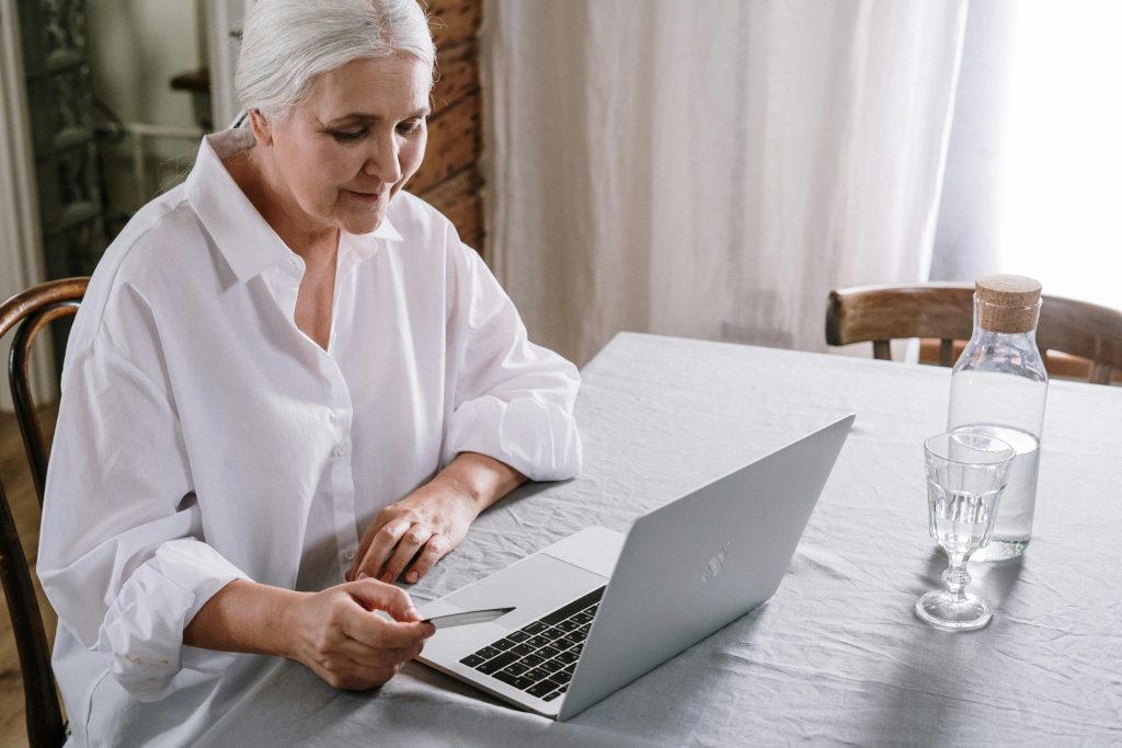 eine ungefähr 70 Jahre alte Frau sucht am Laptop nach Treppenlift Alternativen